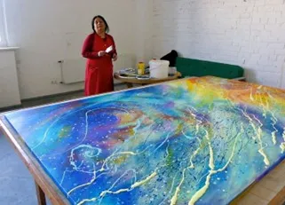Artist with large, colorful abstract painting.